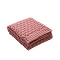 Folded pink knitted blanket on a white background