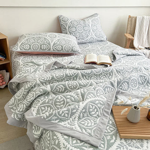 Gray geometric leaf quilt bedding set styled on bed with wooden furniture