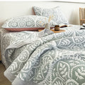 Blue gray geometric leaf quilt bedding set in modern bedroom with minimalist decor
