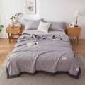 Gray bedding set on a bed in a bedroom with wooden nightstands and decor.