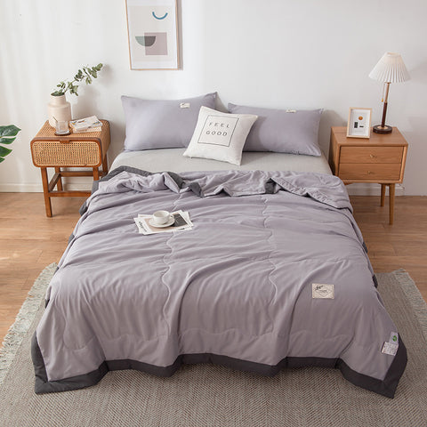 Gray bedding set on a bed in a bedroom with wooden nightstands and decor.