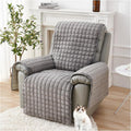Gray quilted armchair cover on a chair with a cat sitting underneath in a home setting.