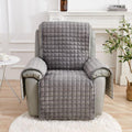 Gray quilted chair cover on a recliner chair in a living room setting.