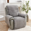 Gray quilted recliner chair in a living room setting with a plant and table.