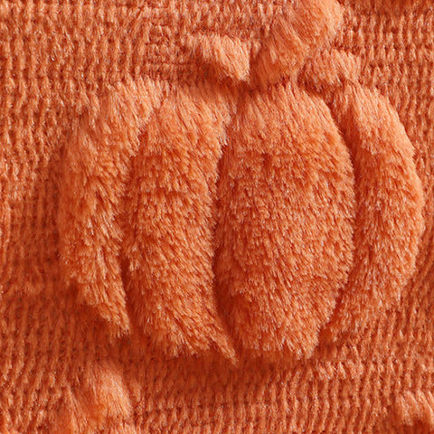 Close-up of a textured orange fabric with tassels