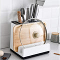 Kitchen utensil holder with cutting board, ladles, and other tools on a kitchen counter.