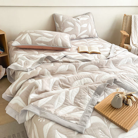Bed with white and gray patterned bedding, pillows, and a wooden side table.