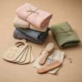 Stack of folded baby blankets with wooden tags, brush, and comb on a beige background