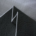 Black textured fabric with white stitching on a light gray background