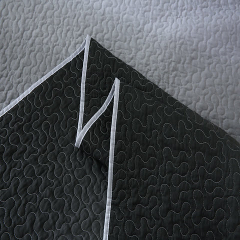 Black textured fabric with white stitching on a light gray background