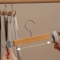 Wooden hanger with adjustable clip being shown on a neutral background