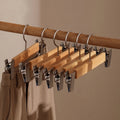 Wooden hangers with clips on a wooden rod against a beige background