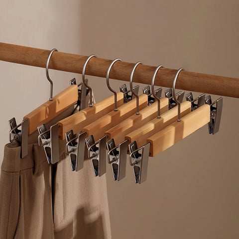 Wooden hangers with clips on a wooden rod against a beige background