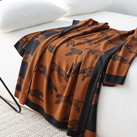 Brown blanket with black border and animal pattern draped over a white surface