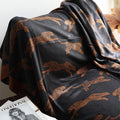 Black blanket with brown animal patterns draped over a surface, with a magazine underneath.