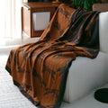 Brown blanket with black animal pattern draped over a white sofa in a living room.