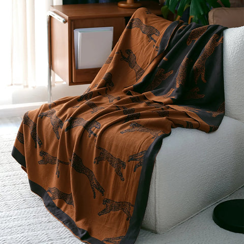 Brown blanket with black animal pattern draped over a white sofa in a living room.