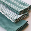 Stack of green and white striped towels on a light background