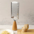 Metal grater with wooden handle on a kitchen counter