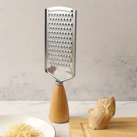 Metal grater with wooden handle on a kitchen counter