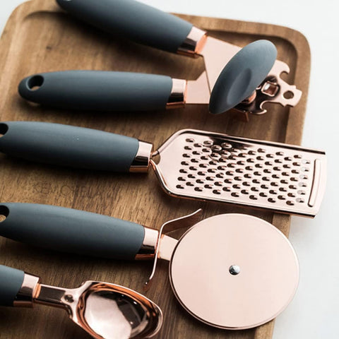 Set of kitchen tools including a grater, garlic press, and other utensils on a wooden surface.