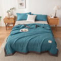 Teal comforter set on a bed in a bedroom with side tables and decor.