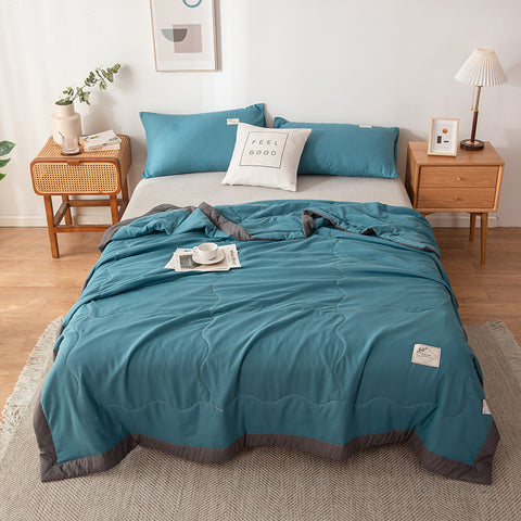 Teal comforter set on a bed in a bedroom with side tables and decor.