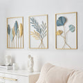 Three framed leaf sculptures on a wall with a white sofa and decor items below.