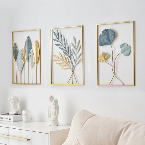 Three framed leaf sculptures on a wall with a white sofa and decor items below.