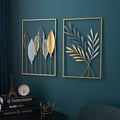 Two decorative wall art pieces with leaf designs on a teal wall.