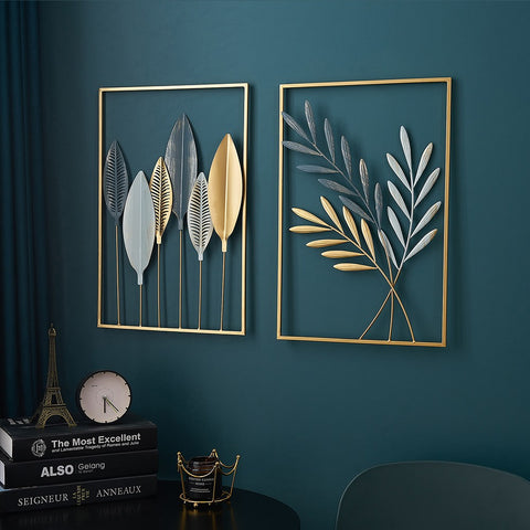 Two decorative wall art pieces with leaf designs on a teal wall.