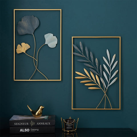 Two framed wall art pieces with floral designs on a dark teal wall.