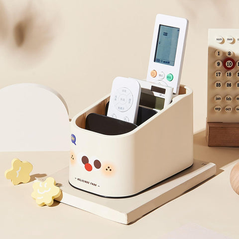 White desk organizer with remote controls and a phone on a beige surface.