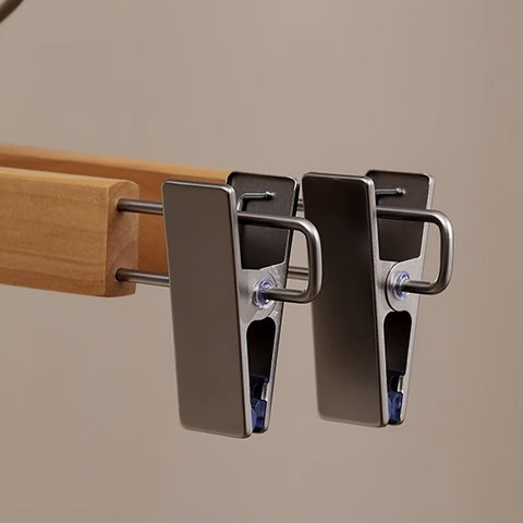 Metal clothespins attached to a wooden rod on a beige background