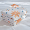 Folded abstract sunny reversible blanket featuring coral and azure abstract shapes, highlighting its lightweight cotton texture.