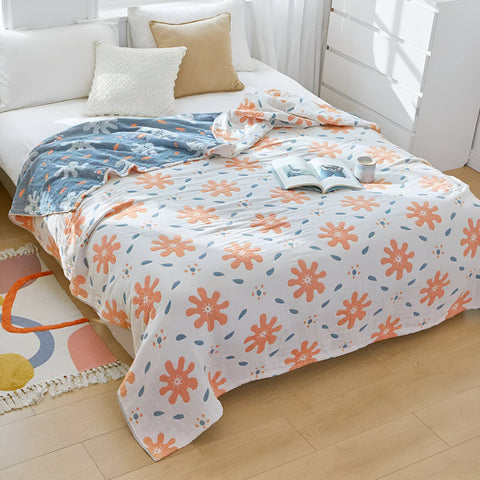 Abstract sunny reversible blanket with coral and azure shapes draped over a cozy bed in a bright room.