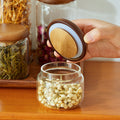 Close-up of airtight acacia wood lid being placed on glass storage jar
