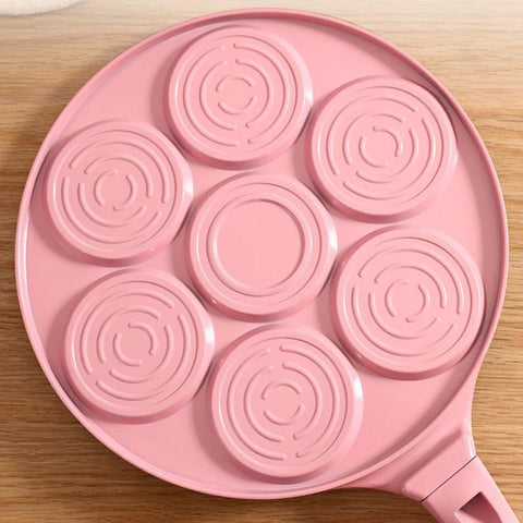  Bottom view of pink Animals Waffle and Pancake Pan showing circular heat distribution rings on wooden table
