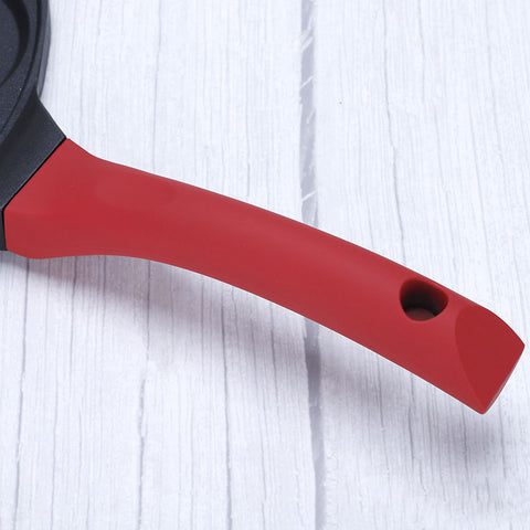 Close-up of red handle on Animals Waffle and Pancake Pan on white wooden surface