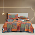 Bed with colorful patchwork quilt and pillows against a beige wall.