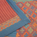 Close-up of quilt with teacup and orange trim throw