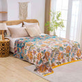  Autumn Garden Cotton Throw Blanket with warm floral patterns draped over a bed in a cozy, natural bedroom setting