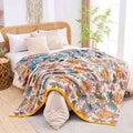 Autumn Garden Cotton Throw Blanket with vibrant floral patterns draped over a cozy bed in a bright, natural-lit bedroom