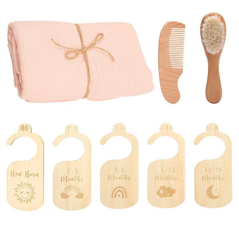 Baby care set with pink blanket, wooden comb, brush, and growth chart markers on a white background.