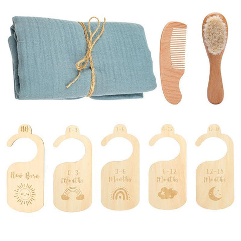 Baby care set with blue muslin cloth, wooden comb, brush, and growth chart markers on a white background.