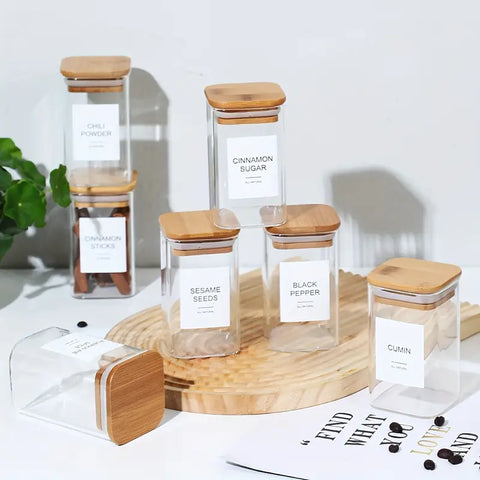Bamboo-lidded spice jars with scoops and custom labels laid out for easy seasoning access.

