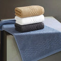 Set of blue, white, and charcoal towels on a beige bench