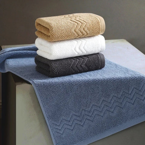 Set of blue, white, and charcoal towels on a beige bench