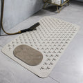 Beige anti-slip bath mat with textured design on a bathroom floor.