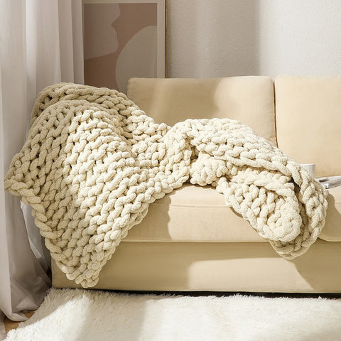 White knitted blanket draped over a beige sofa in a living room.